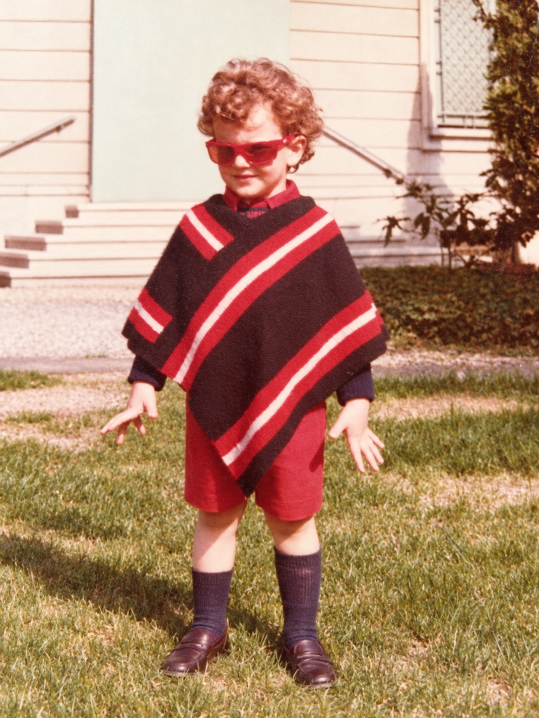 Restored childhood photograph of Ben wearing red sunglasses and a striped poncho.