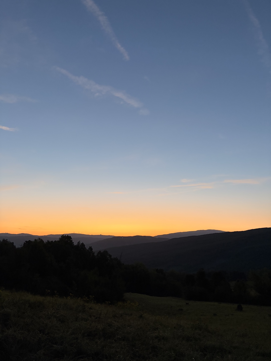 A wide dusk sky above distant dark hills.